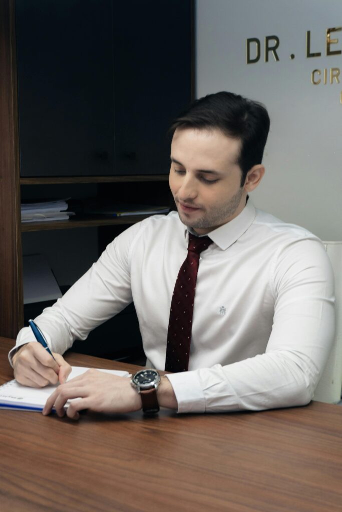 A professional man in an office taking notes in a notebook.